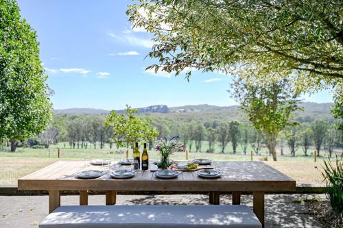 a wooden picnic table with food and wine on it at The Old Dairy at Kangaloon in East Kangaloon