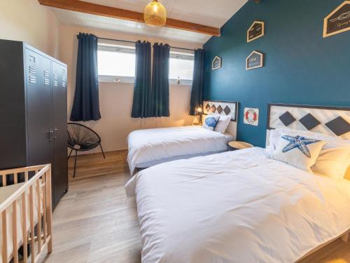 two beds in a room with blue walls at Elegant Place in Goesnes in Goesnes