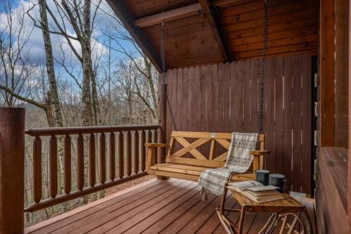 a wooden porch with a swing and a chair on it at Log Cabin, Hot Tub, Fireplace, Pool Table & Views! in Sevierville