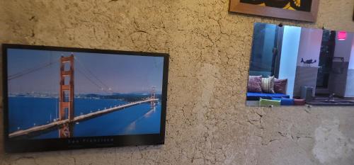 TV colgada en una pared con una foto del puente Golden Gate en Chales Internacional, en Paraty