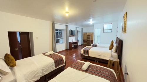 a room with two beds and a living room at Casona Liberty Inn in Cusco