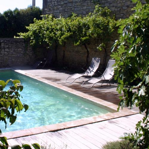 - une piscine avec 2 chaises longues à côté d'un mur en briques dans l'établissement La Rôse, à Saint-Gervasy