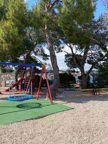 a playground with a swing set in a park at Beach House Tisno whit Sea View in Tisno