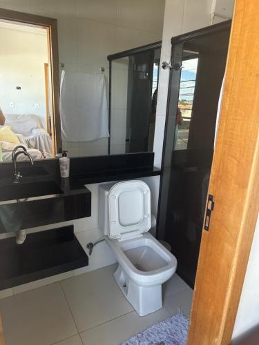 a bathroom with a toilet and a sink and a mirror at Apartamento da Pâm - em frente ao clube cantão in Pontes e Lacerda