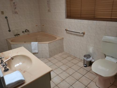 ein Badezimmer mit einem Waschbecken, einem WC und einer Badewanne in der Unterkunft Bundaberg International Motor Inn in Bundaberg