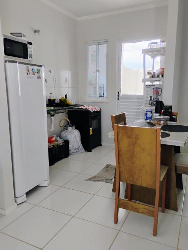 een keuken met een tafel en een witte koelkast bij Casa na Smart city Aquiraz (2a etapa) in Aquiraz