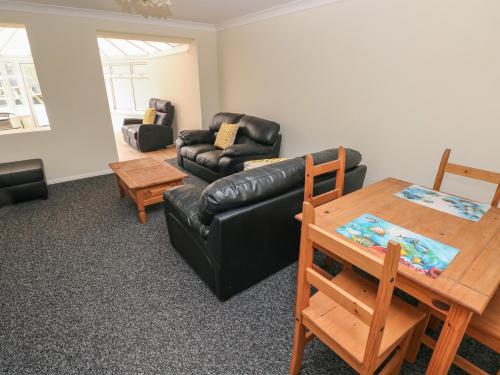 a living room with a black leather couch and a table at 21 Heol Gylfinir in Barry