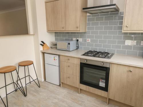a kitchen with a stove and some stools in it at 21 Heol Gylfinir in Barry