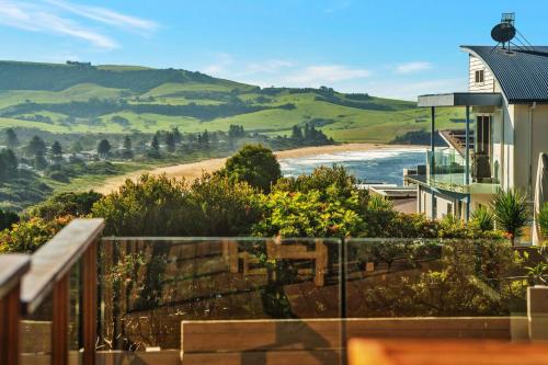 a balcony with a view of a beach and a house at Jane's at Werri, Gerringong in Gerringong