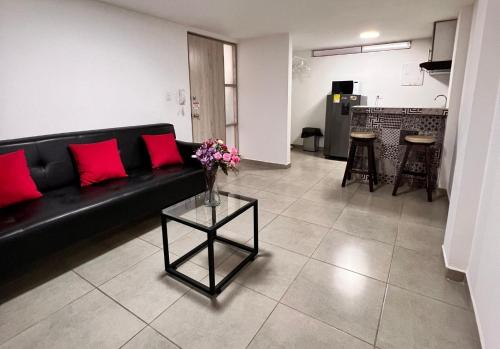 a living room with a black couch and a table with flowers at PARK 2009 Apartaestudios in Cali