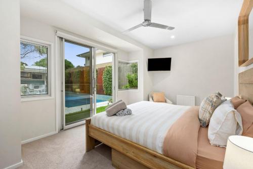 een slaapkamer met een bed en een groot raam bij Caanluje - Pool & Spa, 250m from the Beach in Ocean Grove