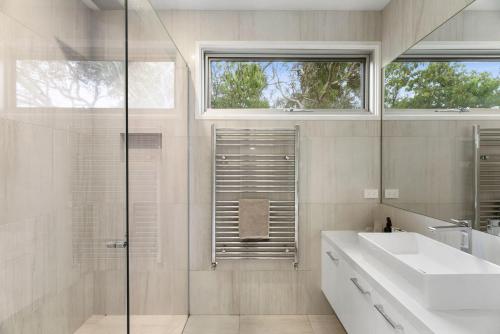 een witte badkamer met een wastafel en een douche bij Caanluje - Pool & Spa, 250m from the Beach in Ocean Grove