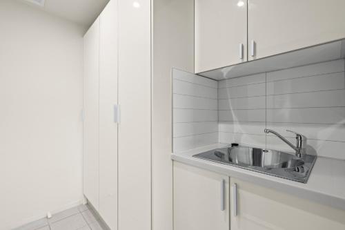 a white kitchen with a sink and white cabinets at Tranquil Tranmere - City Views - Free Parking - Free Wifi in Howrah