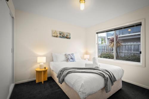 a white bedroom with a bed and a window at Tranquil Tranmere - City Views - Free Parking - Free Wifi in Howrah