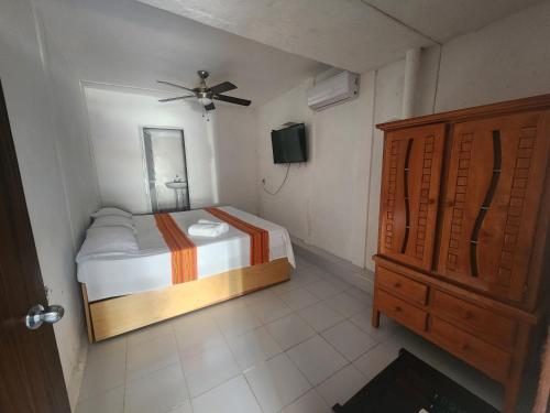 a small bedroom with a bed and a dresser at Casa Lao Bungalow in Zihuatanejo