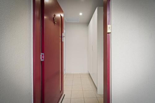 a red door leading into a hallway with a tile floor at Tranquil Tranmere - City Views - Free Parking - Free Wifi in Howrah