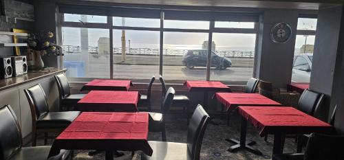 a restaurant with red tables and chairs and a window at North Ocean Hotel in Blackpool