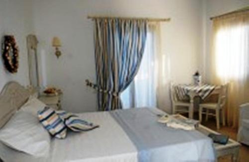 a bedroom with a bed with a table and a window at Caldera Studios in Astypalaia Town