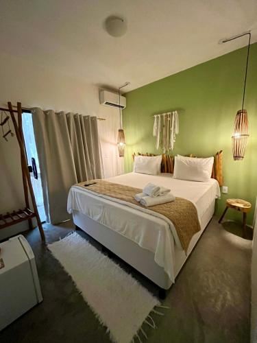 a bedroom with a large bed with a green wall at Jimbaran Pousada & Bristrot in Maragogi