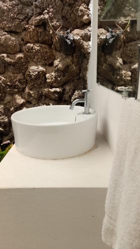 Baño con lavabo blanco y pared de piedra en Managua Backpackers Inn en Managua