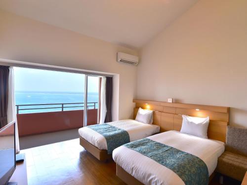 a hotel room with two beds and a large window at Wellness Villa Brisa in Miyako-jima