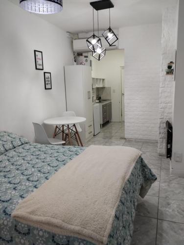 ein Schlafzimmer mit einem Bett und einem Tisch sowie eine Küche in der Unterkunft Mendoza Estudio Urbano in Mendoza