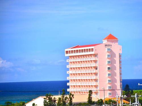 a large pink hotel with the ocean in the background at Wellness Villa Brisa in Miyako Island