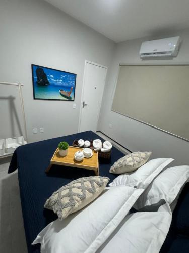 a room with a bed with a table and pillows at Studio 208 Praia de Iracema in Fortaleza