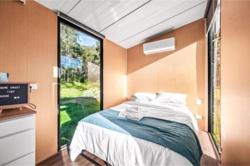 um pequeno quarto com uma cama e uma janela em Yengo Tiny House em Broke