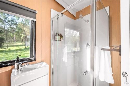 uma casa de banho com um chuveiro, um lavatório e uma janela em Yengo Tiny House em Broke