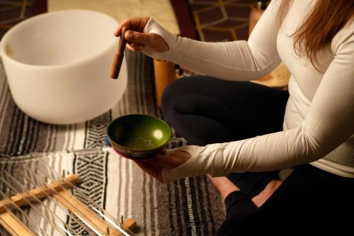 a woman sitting on the floor holding a bowl and a brush at Fairmont Riyadh in Riyadh
