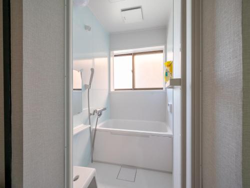 a white bathroom with a tub and a sink at Familia Heiwajima in Tokyo