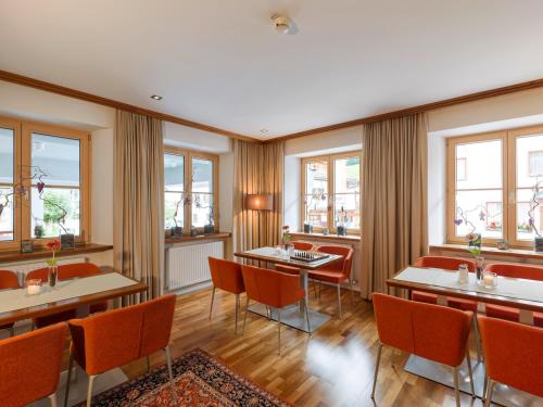 un ristorante con tavoli, sedie e finestre di Quality Hosts Arlberg - Hotel Goldenes Kreuz B&B a Sankt Anton am Arlberg