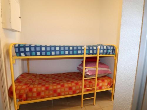 Ce lit superposé se trouve dans une petite chambre dotée d'un couvre-lit. dans l'établissement Studio climatisé avec cabine, terrasse et parking à proximité de la mer - FR-1-307-263, au Grau-du-Roi