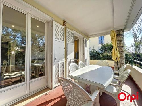 - une terrasse couverte avec une table et des chaises blanches dans l'établissement Villa spacieuse et calme près des plages avec jardin, terrasse, WiFi et climatisation - FR-1-647-32, à Menton