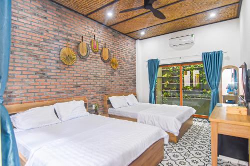 zwei Betten in einem Zimmer mit einer Ziegelwand in der Unterkunft Homestay Phú Mỹ in Phan Thiet
