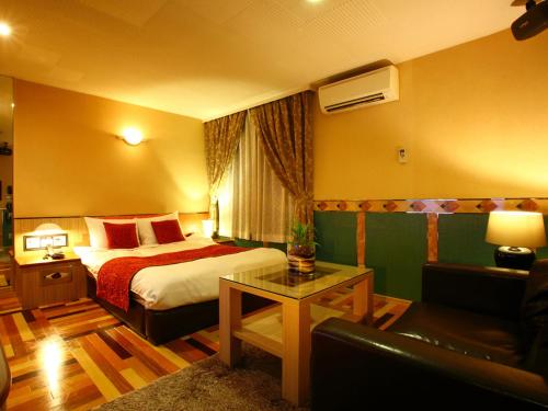 um quarto de hotel com uma cama e um sofá em HOTEL Villamure ogori em Tosu