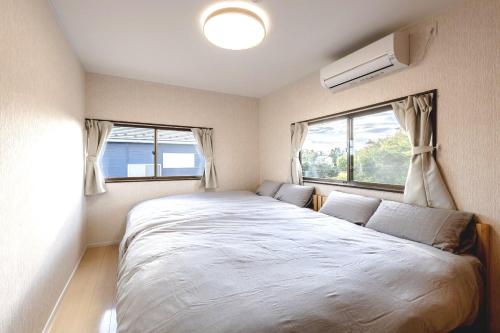 a bedroom with a large bed and two windows at ANGO Kujukuri II in Katakai
