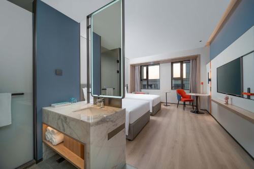 a bathroom with a bed and a sink with a mirror at Holiday Inn Express Suzhou Shihu University Town in Suzhou