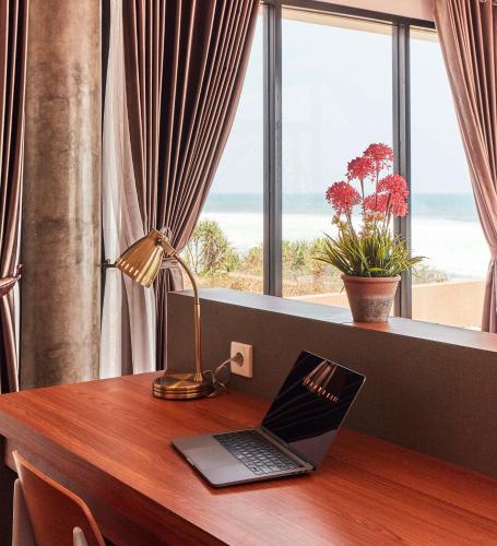 a laptop on a desk with a view of the ocean at Abian Kapas Beach House in Tabanan