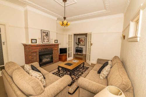 a living room with two couches and a fireplace at Hillside Cottage │ Comfy, Spacious, Walk to CBD & Stannies in Bathurst