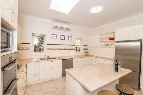 a kitchen with white cabinets and a stainless steel refrigerator at Hillside Cottage │ Comfy, Spacious, Walk to CBD & Stannies in Bathurst