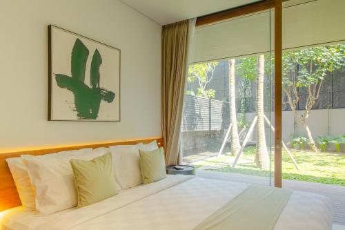 ein Schlafzimmer mit einem Bett und einem großen Fenster in der Unterkunft Domisili Villas Canggu Bali by Fays Hospitality in Canggu