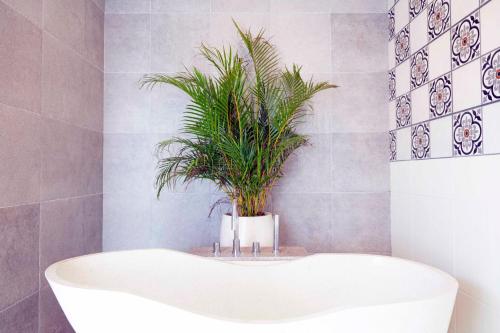 a bathroom with a bath tub with a plant in it at Abian Kapas Beach House in Tabanan