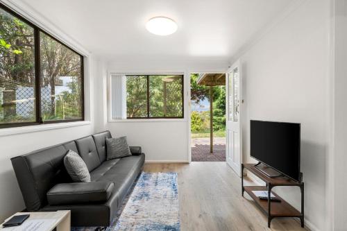 ein Wohnzimmer mit einem Sofa und einem Flachbild-TV in der Unterkunft Narrow Neck - Blissful hideaway in Katoomba