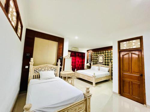a bedroom with two beds and a wooden door at Puri Karang Residence in Bangli