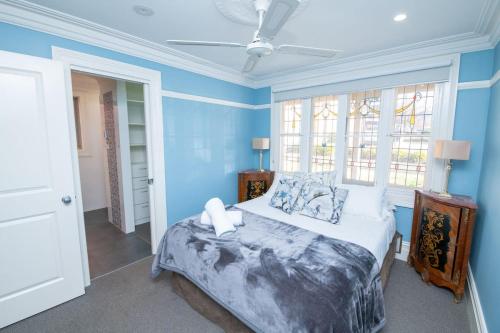um quarto com uma cama com paredes e janelas azuis em Blue Door Apartment 2 - Spacious CBD Apartment em Orange