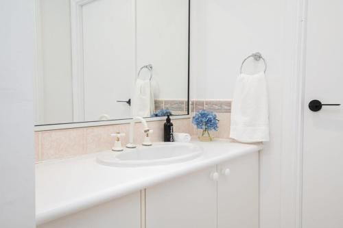 Baño blanco con lavabo y espejo en Darcy Brown House Modern Country Escape, en Orange
