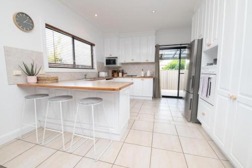 a kitchen with white cabinets and a counter and stools at Villa 88 - Stylish, Modern, Fresh & Light in Orange