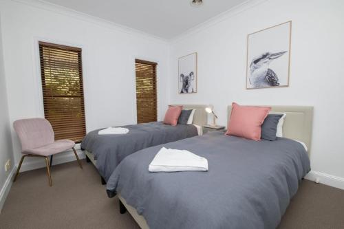 a bedroom with two beds and a chair and windows at Villa 88 - Stylish, Modern, Fresh & Light in Orange